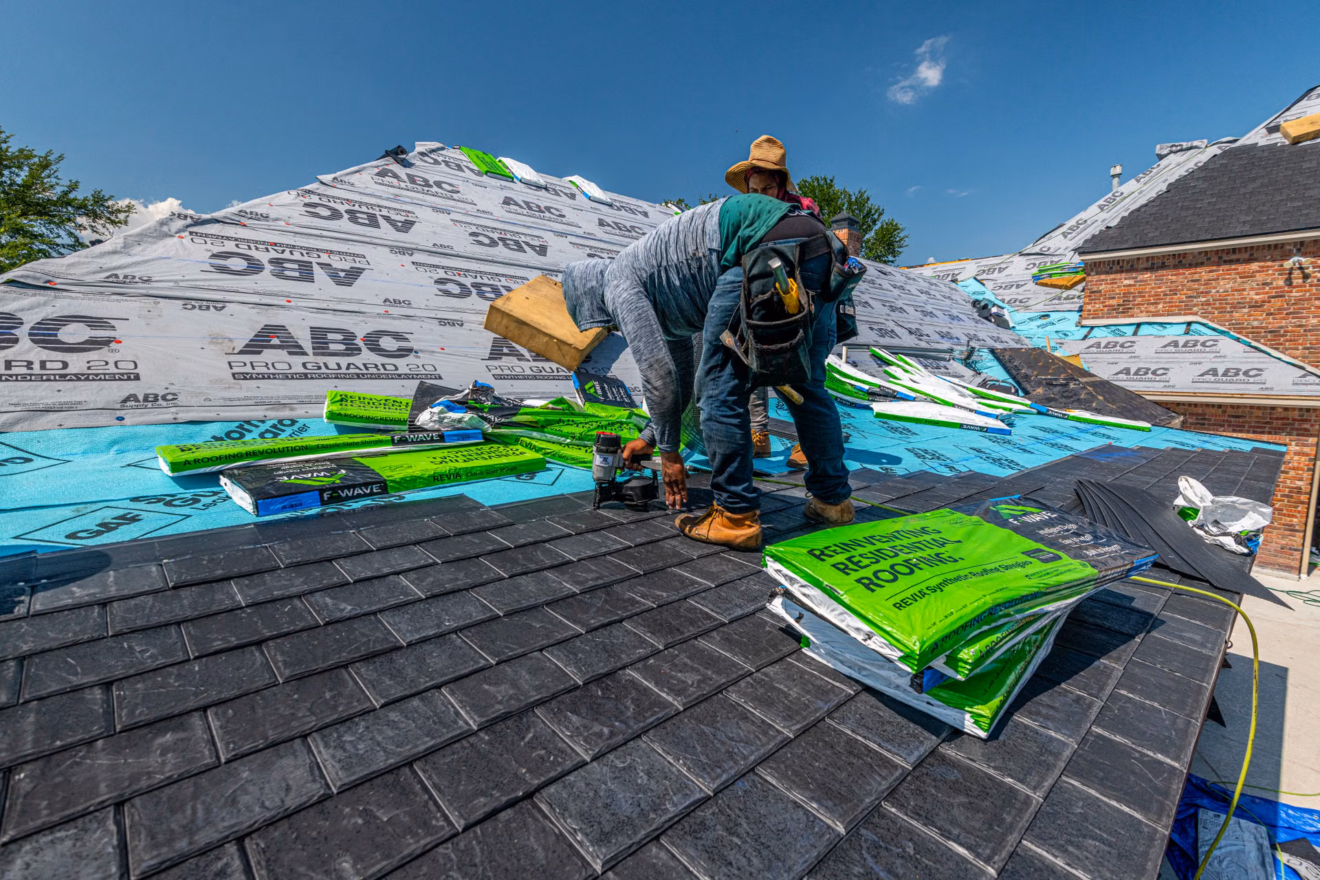Roofing crew installing underlayment and shingles