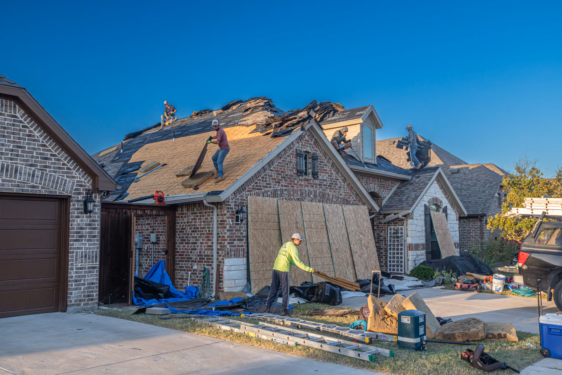 Storm-damaged home mid-reroof with crew working