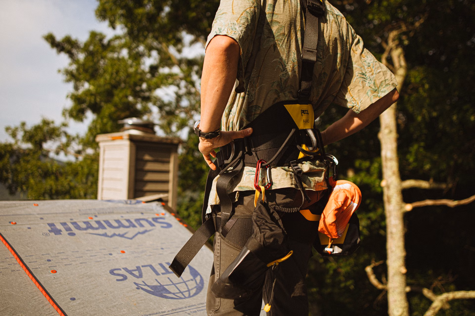 Roofer in a safety harness on a roof with underlayment