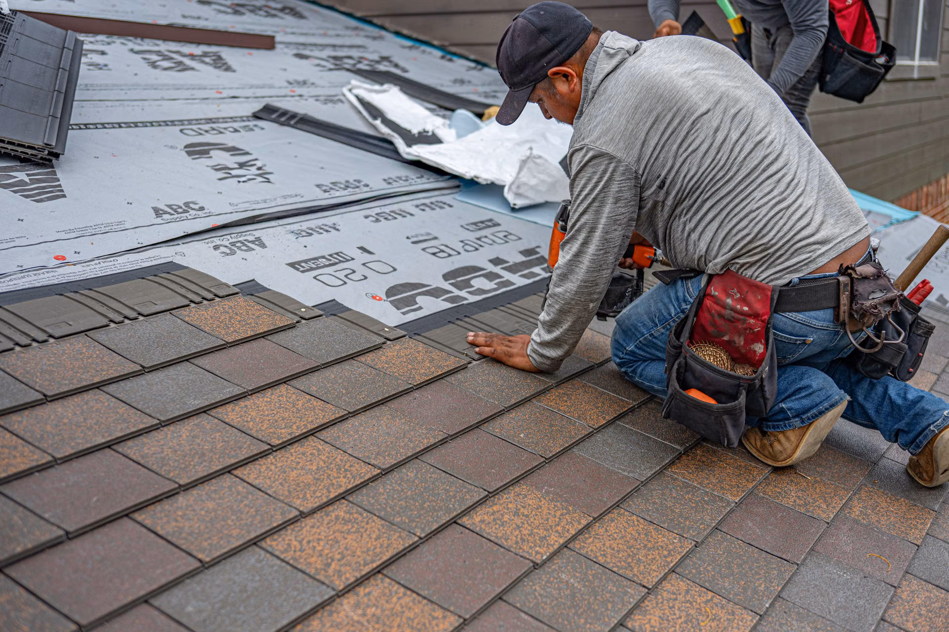 Roofer kneeling to repair a shingle section